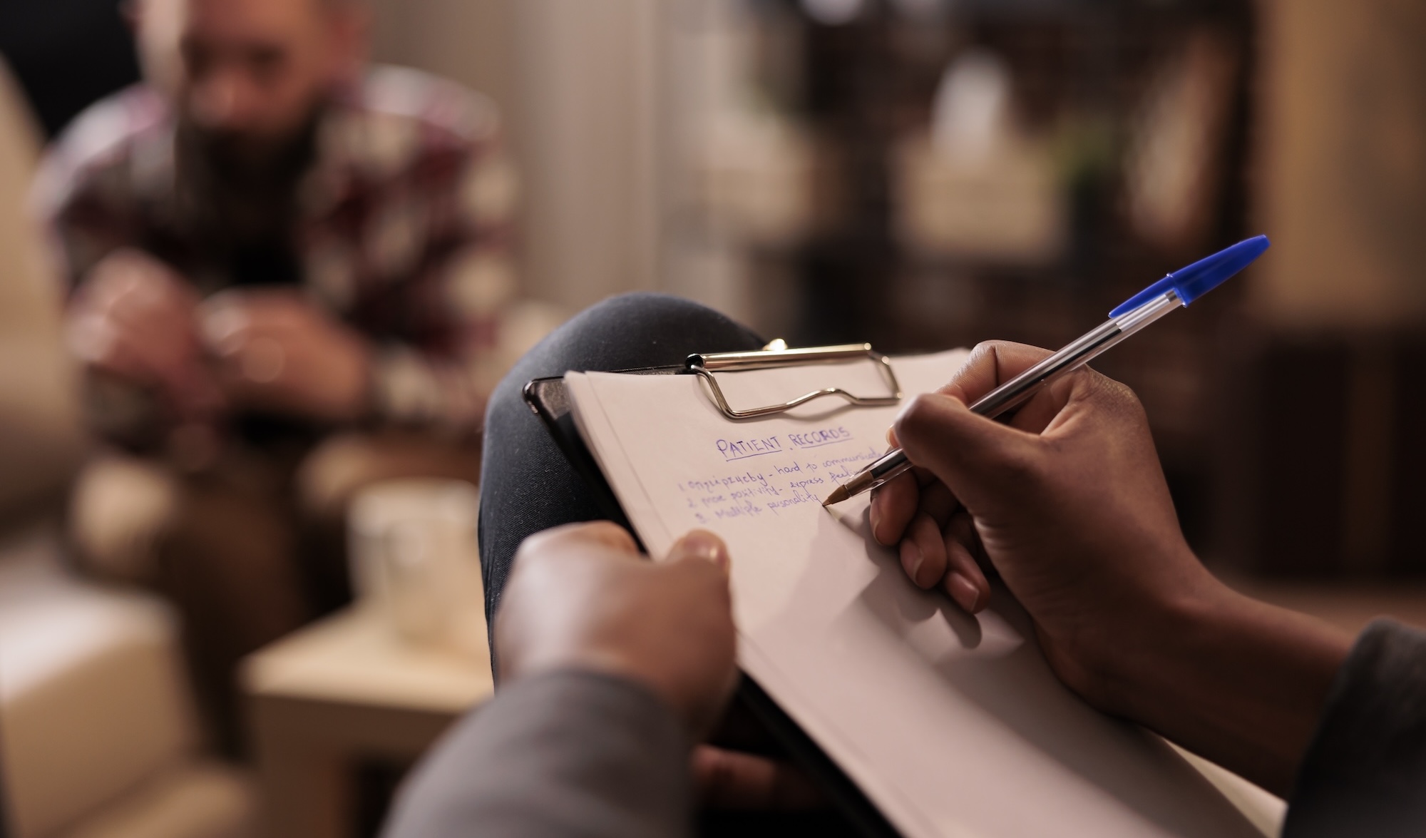 Male psychologist taking notes at couple therapy session to help with relationship issues, counselor giving advice. Explaining marriage problems, using paper to do psychoanalysis. Close up,
